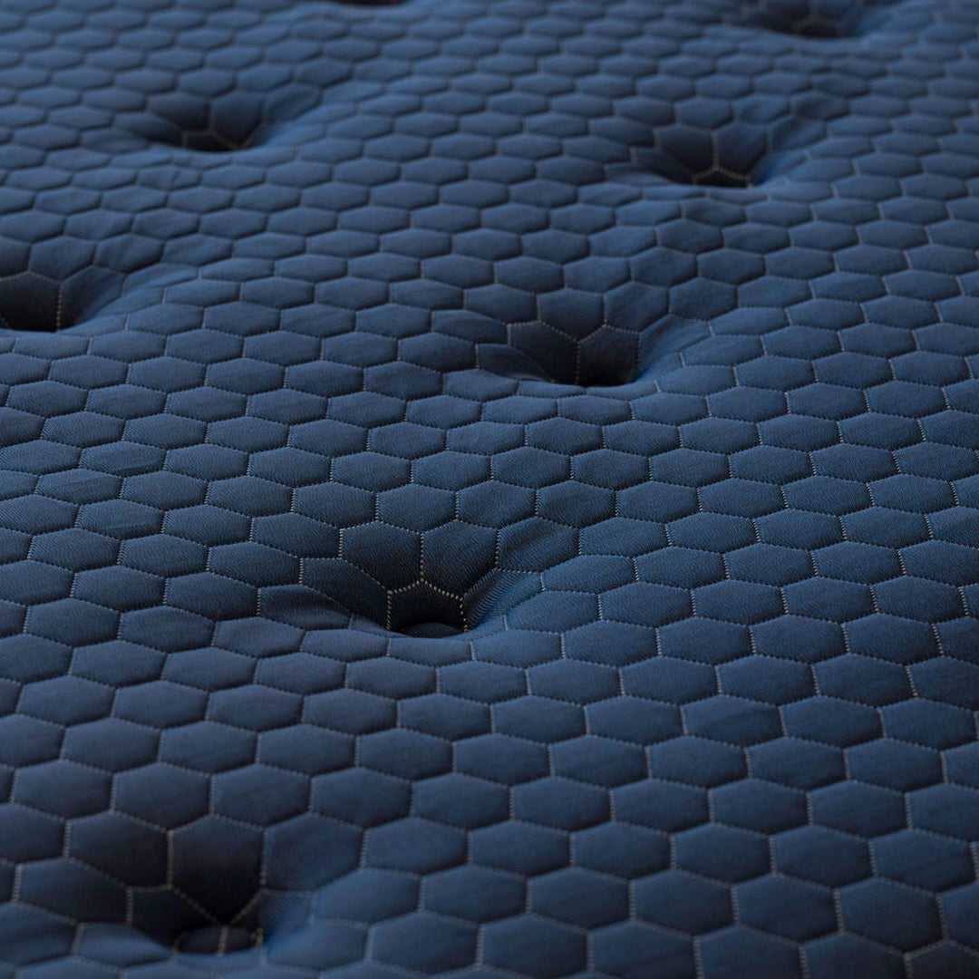Close-up of the Brooklyn Bedding Signature Hybrid quilted cover with hexagonal stitching pattern and tufted Euro-top detail in deep blue performance fabric