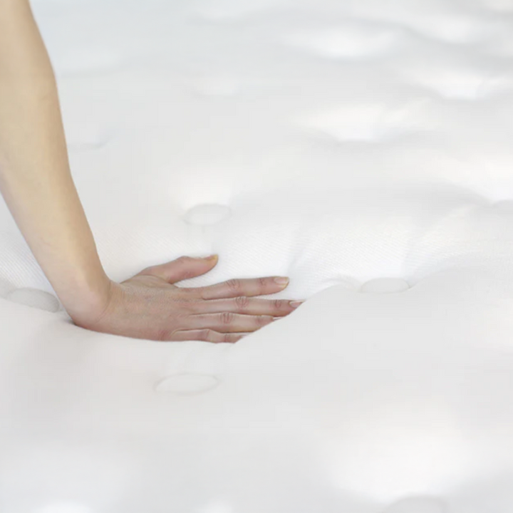 A hand pressing the WinkBed Hybrid Tencel quilted cover to show its plush pillow-top feel